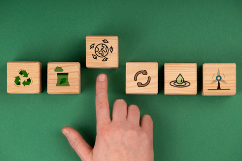 Wooden blocks with sustainability icons, including recycling, waste reduction, and renewable energy, symbolizing key principles of the circular economy.