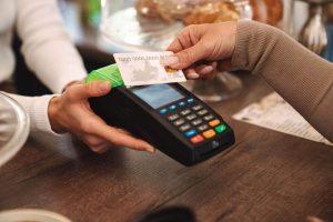A customer makes a contactless payment with a bank card, illustrating the growing popularity of credit cards with health and wellness rewards that promote smarter spending and healthier lifestyles.