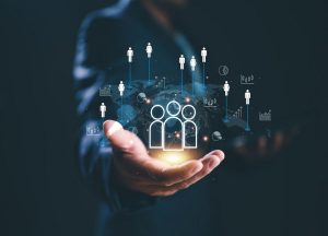 A businessman holding a glowing digital icon of people connected worldwide, symbolizing diversity, inclusion, and the global impact of thematic investments.