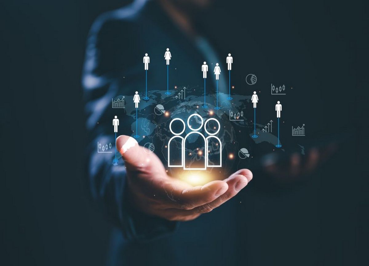 A businessman holding a glowing digital icon of people connected worldwide, symbolizing diversity, inclusion, and the global impact of thematic investments.